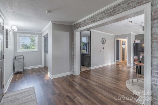 foyer with dark wood-type flooring, ornamental molding, and a textured ceiling