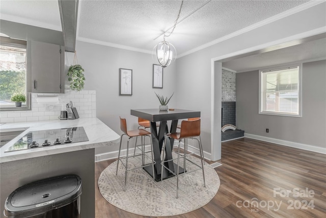 dining room featuring dark wood-type flooring, a chandelier, crown molding, and a textured ceiling