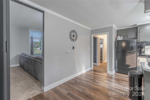 kitchen with a textured ceiling, gray cabinetry, black appliances, hardwood / wood-style floors, and ornamental molding