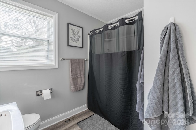 bathroom featuring curtained shower, hardwood / wood-style floors, toilet, and a textured ceiling