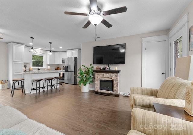 living room with ceiling fan, hardwood / wood-style flooring, and a fireplace