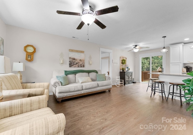 living room featuring dark wood-type flooring and ceiling fan