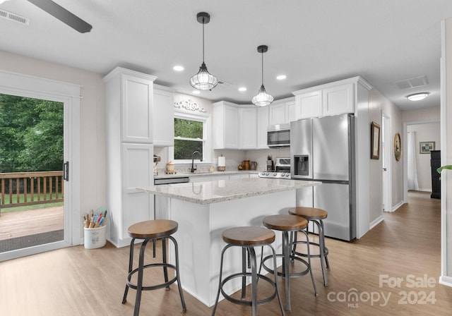 kitchen with light wood-type flooring, stainless steel appliances, sink, ceiling fan, and white cabinets