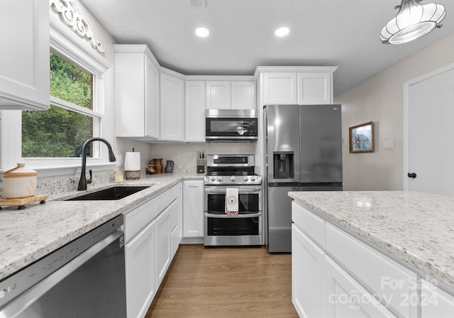 kitchen featuring white cabinets, appliances with stainless steel finishes, hardwood / wood-style floors, and sink