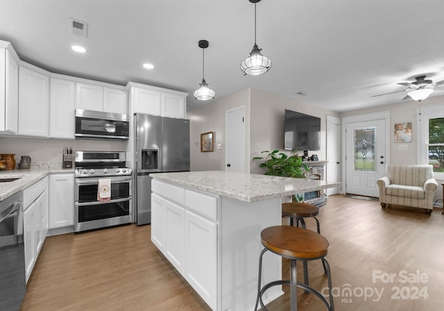 kitchen featuring ceiling fan, a kitchen island, stainless steel appliances, and white cabinets