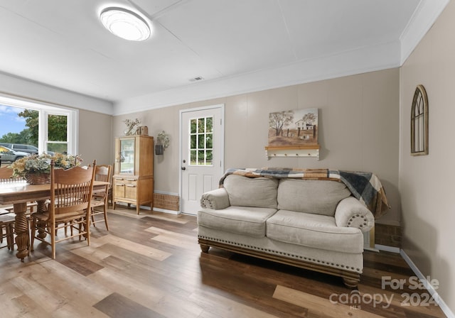 living room with hardwood / wood-style flooring, ornamental molding, and a healthy amount of sunlight