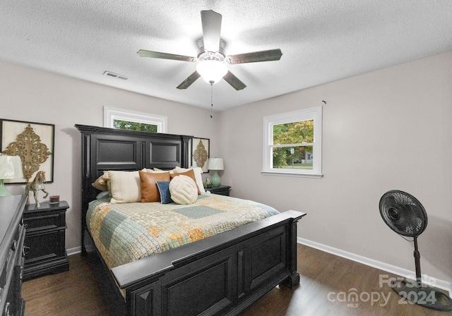 bedroom featuring multiple windows, a textured ceiling, ceiling fan, and dark hardwood / wood-style floors