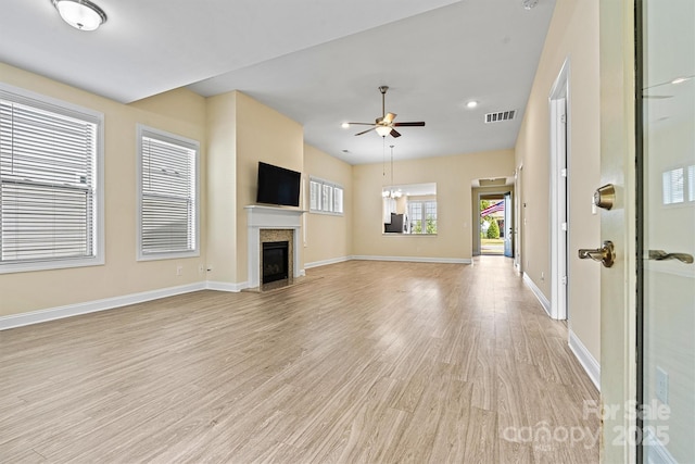 unfurnished living room with a ceiling fan, baseboards, visible vents, a fireplace, and light wood-type flooring