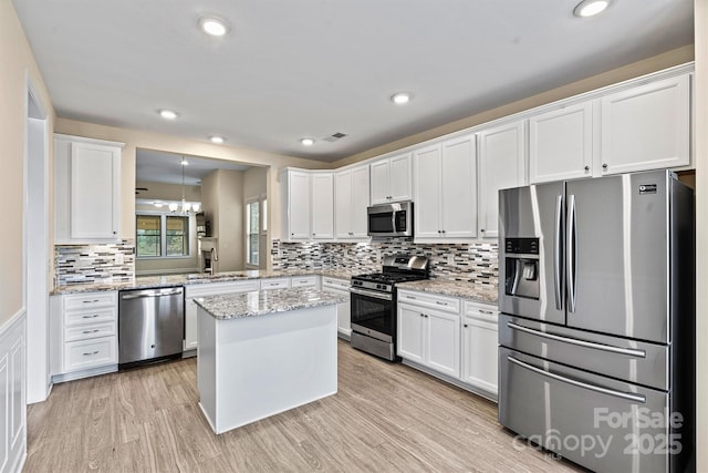 kitchen with light wood-style flooring, a sink, appliances with stainless steel finishes, white cabinetry, and tasteful backsplash