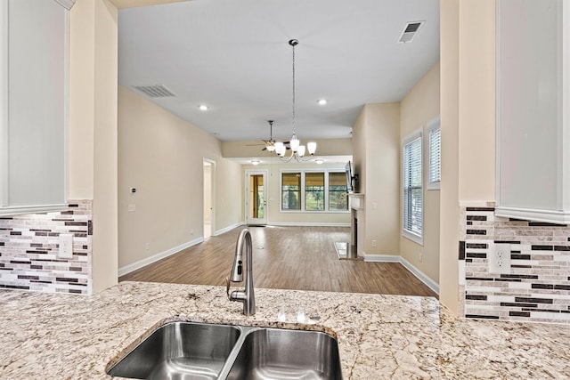 kitchen featuring a sink, visible vents, light stone countertops, and open floor plan