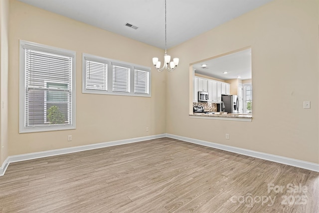 unfurnished room featuring visible vents, baseboards, an inviting chandelier, and light wood finished floors