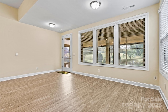 unfurnished room with visible vents, baseboards, and wood finished floors