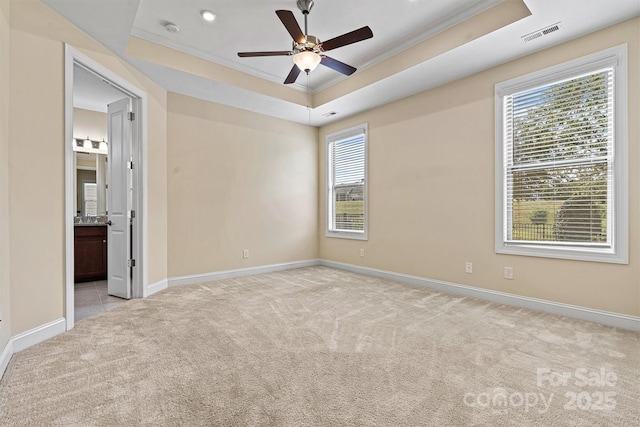 unfurnished room featuring visible vents, a raised ceiling, light colored carpet, and ornamental molding