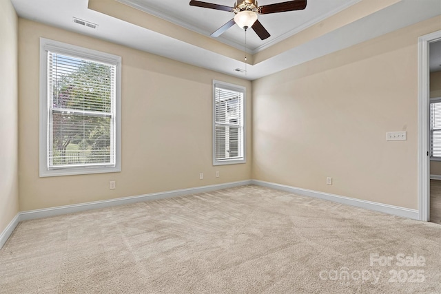 carpeted spare room with a wealth of natural light, crown molding, a raised ceiling, and baseboards