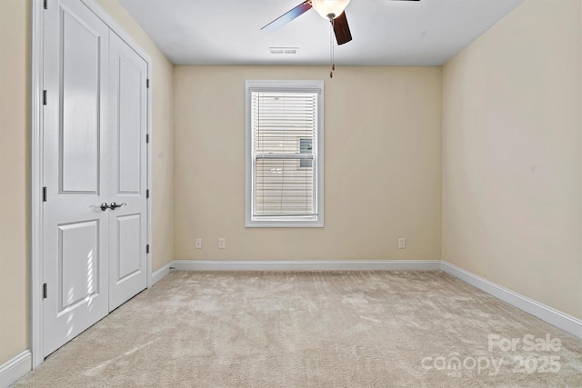 unfurnished bedroom featuring light carpet, visible vents, a ceiling fan, and baseboards