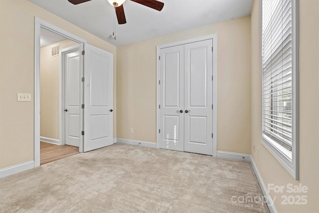 unfurnished bedroom featuring visible vents, a ceiling fan, a closet, carpet flooring, and baseboards