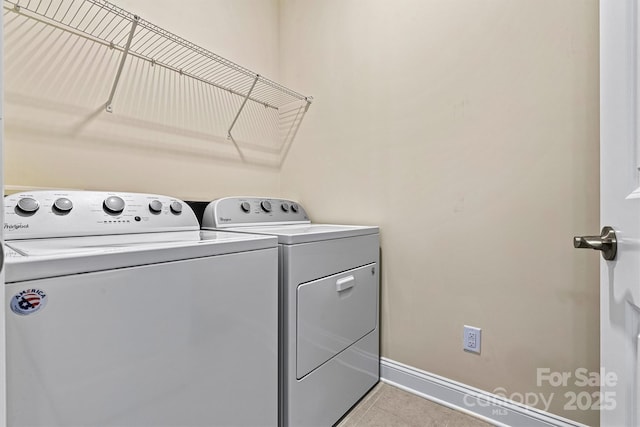 washroom featuring light tile patterned floors, baseboards, washing machine and dryer, and laundry area