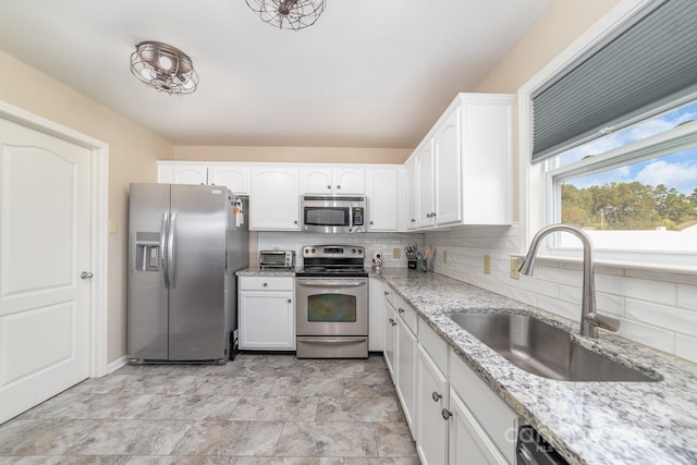 kitchen featuring appliances with stainless steel finishes, white cabinetry, sink, and decorative backsplash