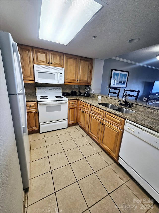 kitchen with white appliances, sink, kitchen peninsula, light tile patterned flooring, and a textured ceiling