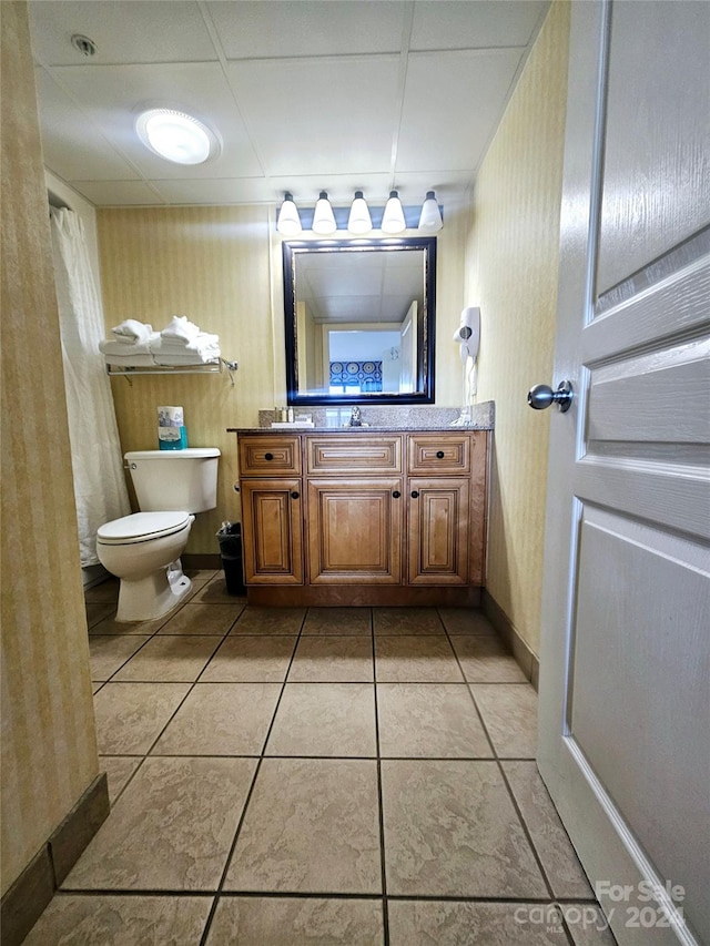 bathroom featuring vanity, toilet, a paneled ceiling, and tile patterned floors