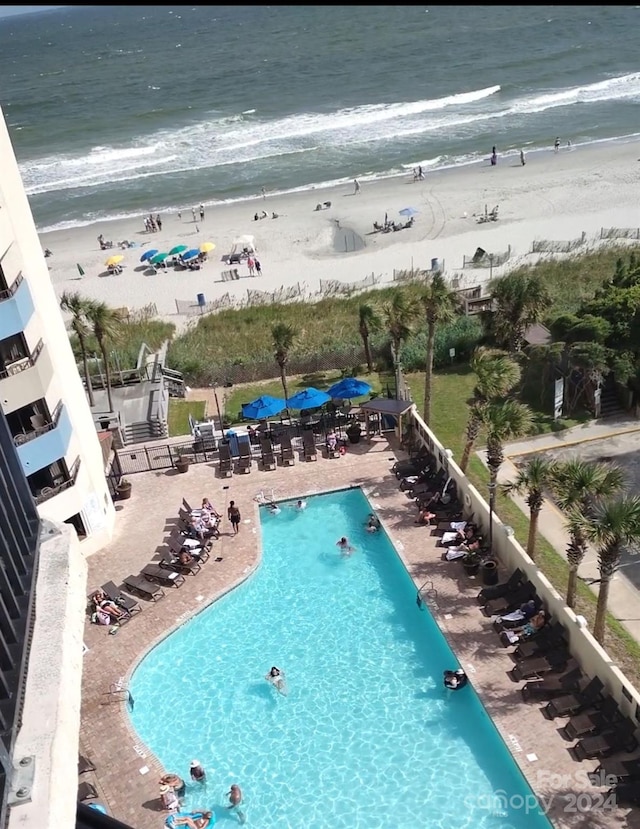 view of pool featuring a view of the beach, a patio, and a water view