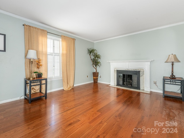 unfurnished living room with wood-type flooring, crown molding, and a high end fireplace