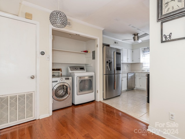 laundry room with ceiling fan, independent washer and dryer, crown molding, and light hardwood / wood-style flooring