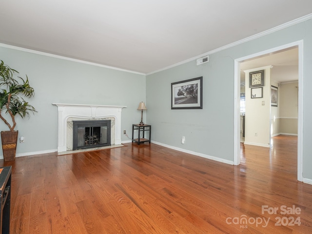 unfurnished living room with hardwood / wood-style flooring, ornamental molding, and a fireplace