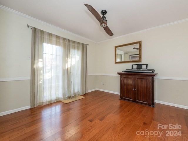 spare room featuring wood-type flooring, ceiling fan, and crown molding