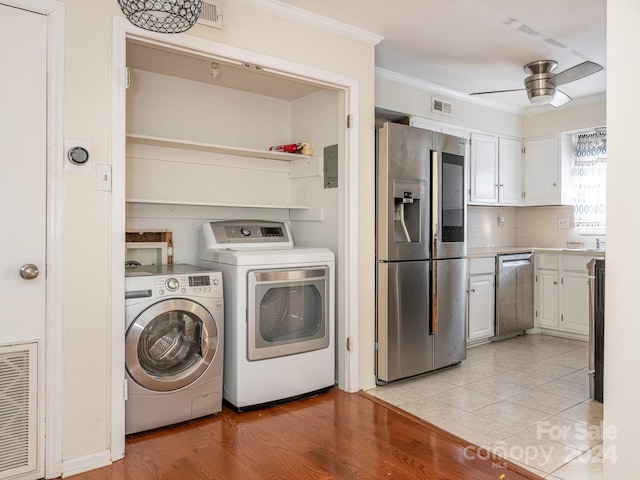 clothes washing area with light wood-type flooring, washer and clothes dryer, ornamental molding, and ceiling fan