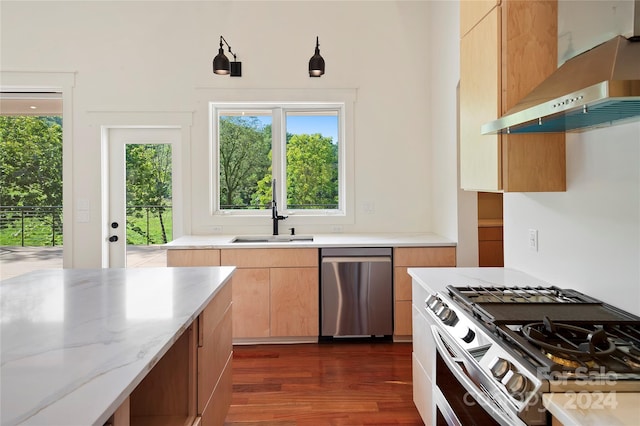 kitchen featuring dark hardwood / wood-style flooring, light stone counters, sink, wall chimney exhaust hood, and appliances with stainless steel finishes