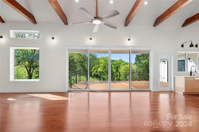 unfurnished room featuring beamed ceiling, sink, ceiling fan, and light hardwood / wood-style floors