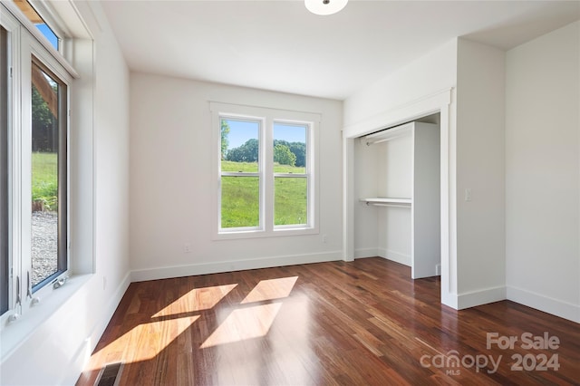 unfurnished bedroom with dark hardwood / wood-style flooring and a closet