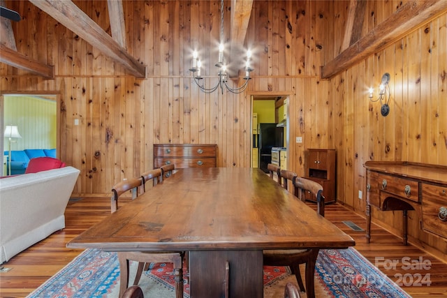 dining area featuring hardwood / wood-style floors, wooden walls, and beamed ceiling