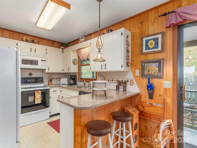 kitchen featuring sink, kitchen peninsula, white appliances, and a wealth of natural light