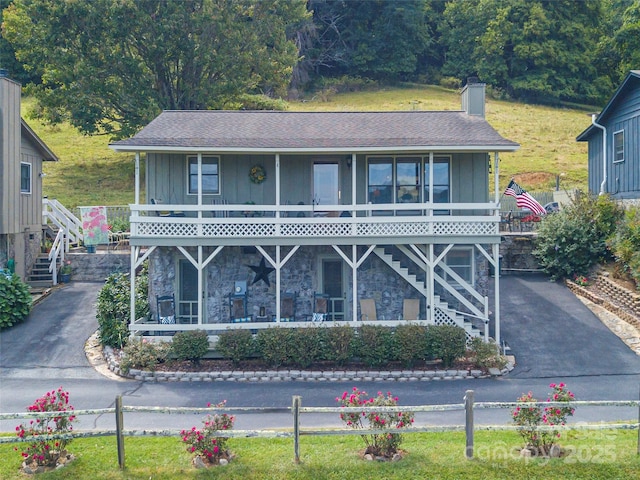 view of front of home featuring aphalt driveway, board and batten siding, and stairway