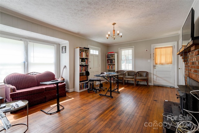 living room with an inviting chandelier, dark hardwood / wood-style floors, ornamental molding, and a textured ceiling