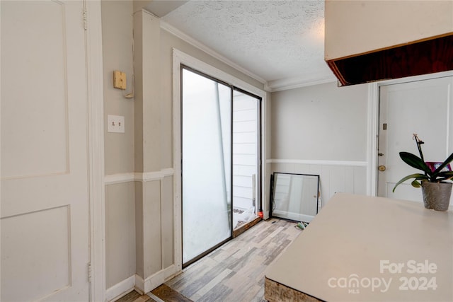 dining space with a textured ceiling, light hardwood / wood-style flooring, and crown molding