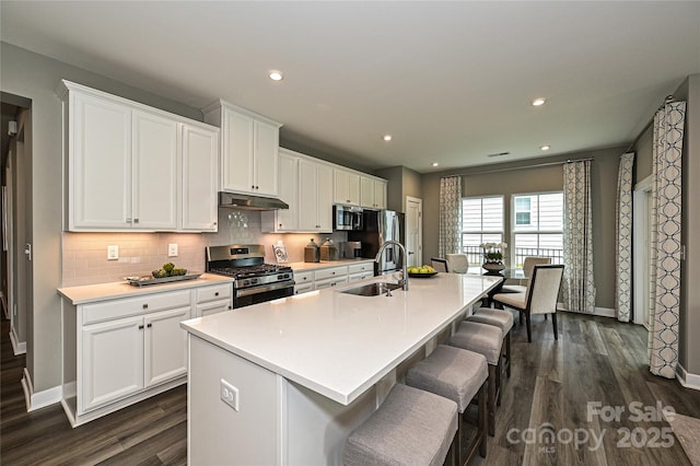 kitchen featuring white cabinets, stainless steel appliances, and a center island with sink