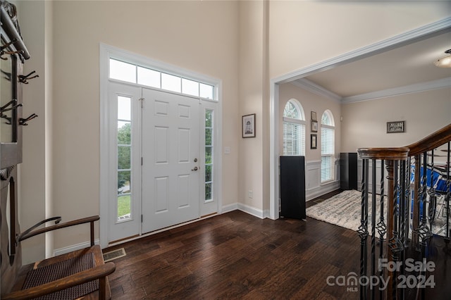 foyer with baseboards, a high ceiling, dark wood finished floors, and crown molding