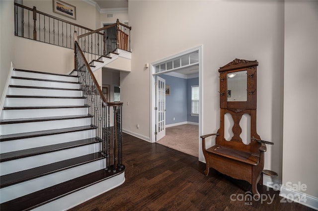 stairway with wood finished floors, baseboards, visible vents, a high ceiling, and crown molding