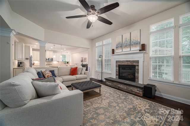 living room with ceiling fan, a fireplace, dark hardwood / wood-style floors, and ornate columns