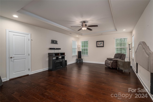 living room with ornamental molding, a raised ceiling, ceiling fan, and dark hardwood / wood-style floors