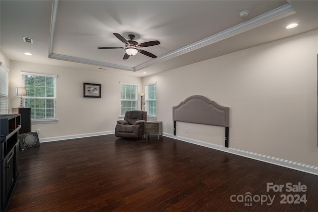 living area with wood finished floors, visible vents, a tray ceiling, ceiling fan, and crown molding