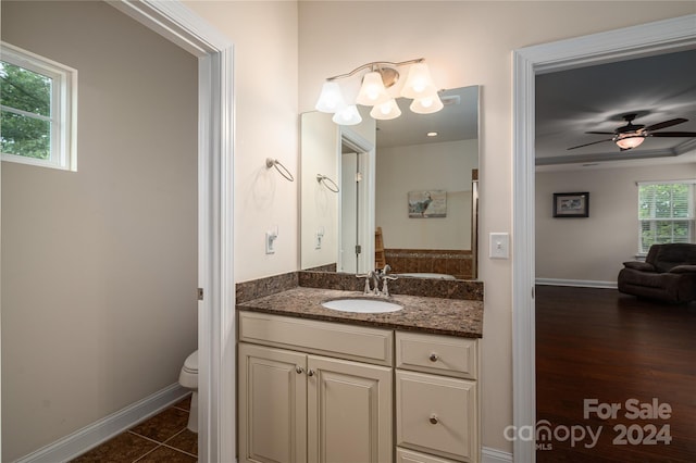 bathroom featuring tile patterned flooring, baseboards, toilet, vanity, and a ceiling fan
