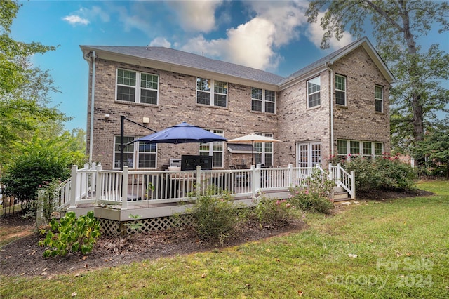 back of property featuring a yard, brick siding, and a wooden deck
