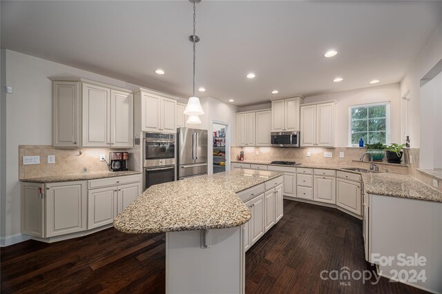 kitchen with hanging light fixtures, dark hardwood / wood-style floors, appliances with stainless steel finishes, and white cabinets