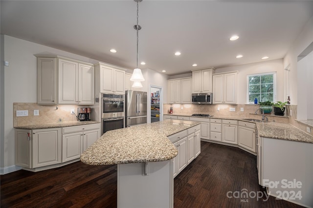 kitchen with tasteful backsplash, a center island, dark wood-type flooring, appliances with stainless steel finishes, and a sink