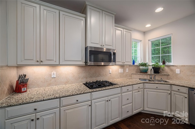 kitchen with a sink, backsplash, recessed lighting, stainless steel appliances, and light stone countertops