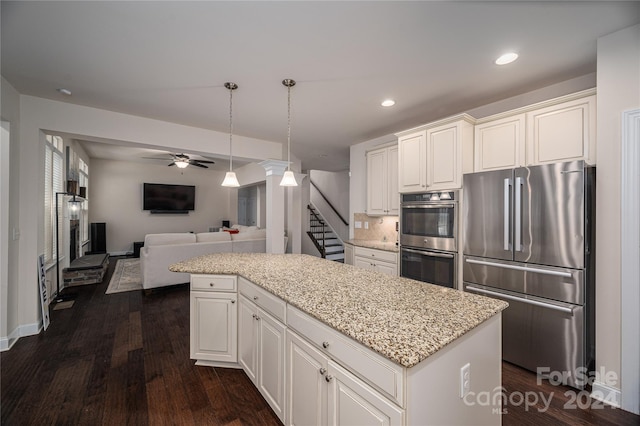 kitchen with a kitchen island, open floor plan, appliances with stainless steel finishes, a ceiling fan, and dark wood-style flooring